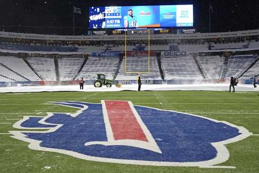 Workers clear snow in Highmark Stadium in preparation for a Sunday Night Football game between the …