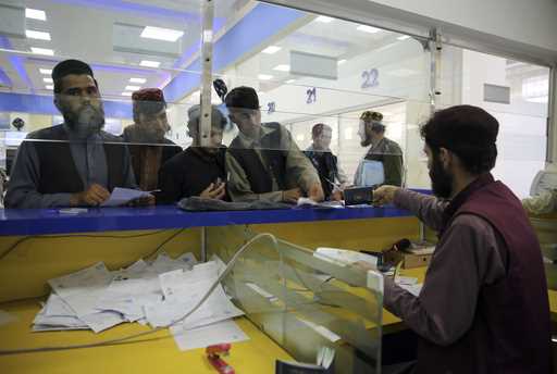 Afghan men wait to receive their passports from the main post office in the city of Kabul, Afghanis…