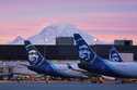 Alaska Airlines planes are shown parked at gates with Mount Rainier in the background at sunrise, M…