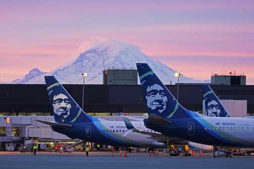 Alaska Airlines planes are shown parked at gates with Mount Rainier in the background on March 1, 2…