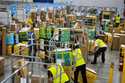 Amazon employees load packages on carts before being put on to trucks for distribution for Amazon's…