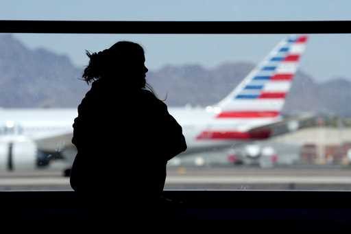 A woman waits for her flight as an American Airlines jet passes by at Sky Harbor airport on March 4…