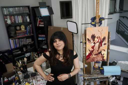 Artist Karla Ortiz poses next to one of her paintings, right, in San Francisco, August 4, 2023
