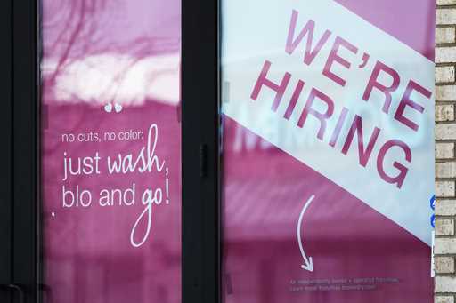 A hiring sign is displayed at a hair salon in Vernon Hills, Ill