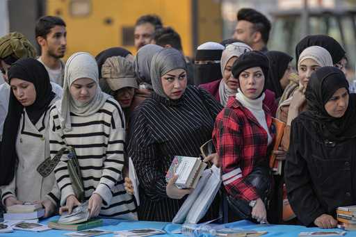 People browse through books displayed during the annual book festival in Abu Nawas street in centra…