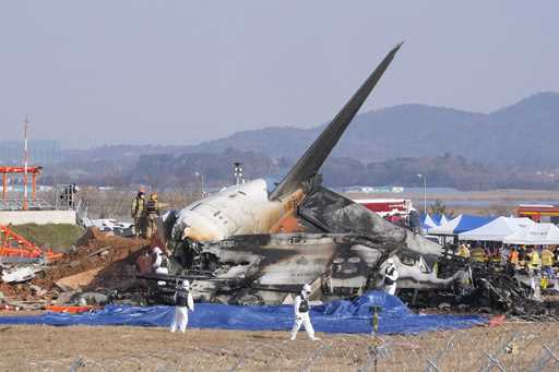 Firefighters and rescue team members work near the wreckage of a passenger plane at Muan Internatio…