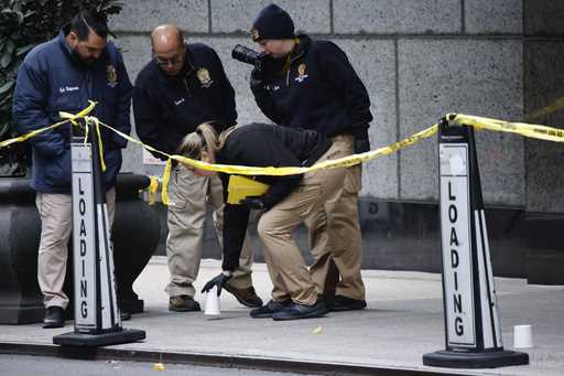 Members of the New York police crime scene unit pick up cups marking the spots where bullets lie as…