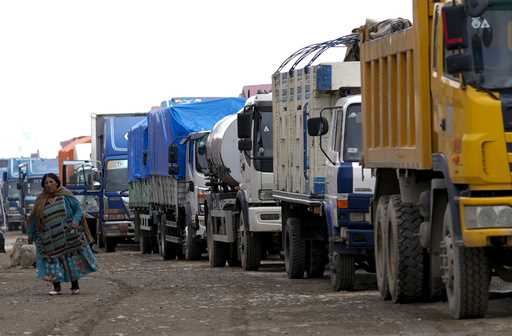 A woman walks next to a queue of truck drivers waiting to fill their diesel tanks in El Alto, Boliv…