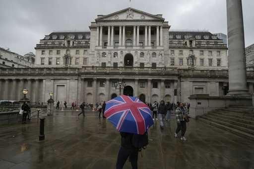 FILE -A woman with an umbrella stands in front of the Bank of England, at the financial district in…