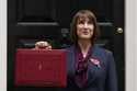 Britain's Chancellor of the Exchequer, Rachel Reeves, looks up as she holds up the traditional red …