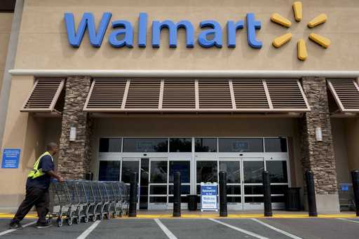 In this May 9, 2013, file photo, a worker pushes shopping carts in front of a Wal-Mart store in La …