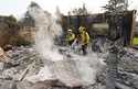 Firefighters extinguish burning embers at a house on Santa Rosa Avenue, also known as Christmas Tre…