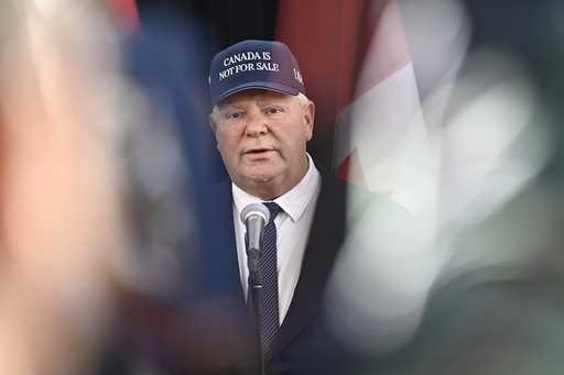 Ontario Premier Doug Ford, wearing a 'Canada Is Not For Sale' hat, speaks as he arrives for a first…