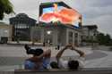 Chinese men rest near a screen depicting a phoenix at a mall in Beijing, on June 11, 2024