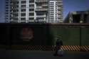 A woman carrying her belonging walks by a luxury housing construction site in Beijing, on Sept