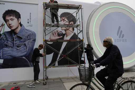 Workers install billboards outside a mall in Beijing, Friday, October 18, 2024