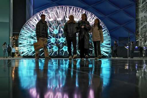 Shoppers walk around art light structures on display at a popular outdoor shopping mall in Beijing,…