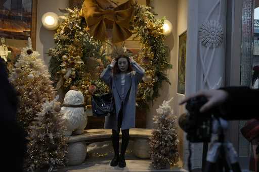 A woman poses for photos near Christmas decorations at a popular mall in Beijing, Sunday, December …