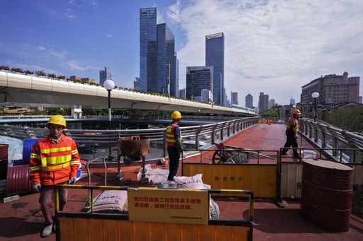 Workers refurbish an overhead pedestrian bridge in Shanghai, Wednesday, October 9, 2024