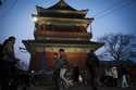 Residents cross an intersection in front of drum tower in the evening in downtown Beijing, China, S…