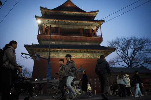 Residents cross an intersection in front of drum tower in the evening in downtown Beijing, China, S…