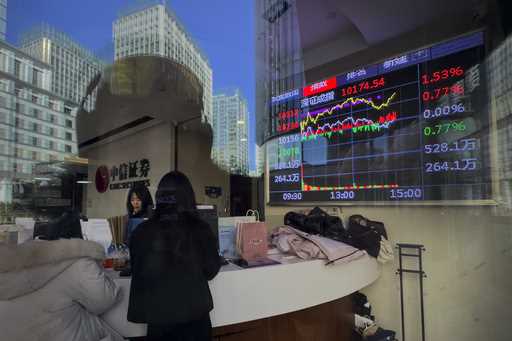 Women stand near an electronic board displaying Shenzhen shares trading index at a brokerage house …