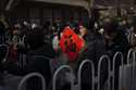 A woman holds a red paper with Chinese calligraphy "Good Fortune" as people line up to get the red …