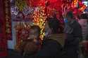 A woman carries a child as she shops at a New Year bazaar set up for the upcoming Chinese Lunar New…