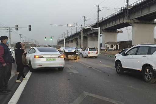 This photo provided by Zhang Yazhou shows her damaged Tesla Model 3, left, which her father was dri…