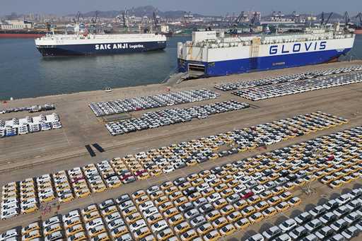 Vehicles and trucks for export wait for transportation from a port in Yantai in eastern China's Sha…