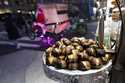 Chestnuts are displayed at a food vendor as a person dressed as Santa Claus offers rides, Thursday,…