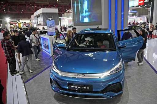 People inspect electric vehicles made by Chinese automaker BYD during an auto fair in Jakarta, Indo…