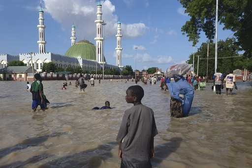 People walk through floodwaters following a dam collapse in Maiduguri, Nigeria, Tuesday, Sept 10, 2…