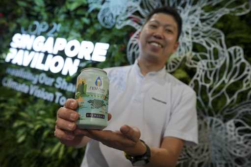 Nick Chow, part of the COP29 Singapore Pavilion team, poses for a photo with NEWBrew, beer made wit…