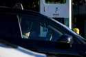 A driver waits in their car while charging their electric vehicles at an Electrify America station,…