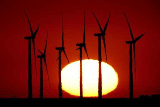 Wind turbines at the Buckeye Wind Energy are diffused by heat vapors as the are silhouetted against…