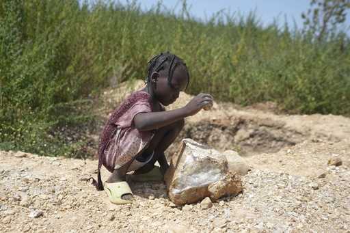 Juliet Samaniya, 6, carries a bag of lithium with other children at an illegal mining site in Pasel…