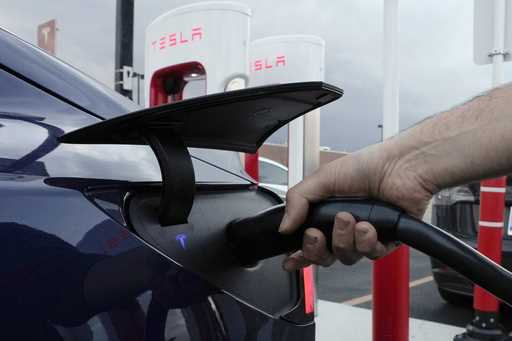 A motorist charges his electric vehicle at a Tesla Supercharger station in Detroit, November 16, 20…