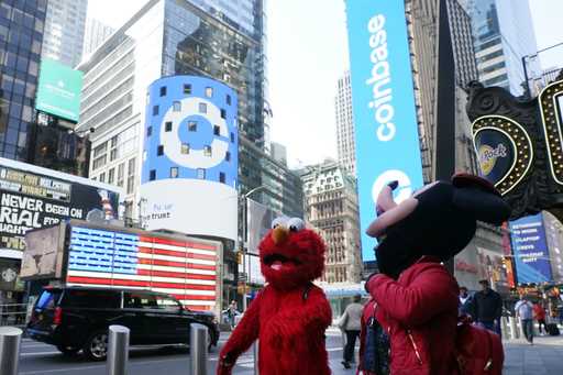 Costumed characters pass the Nasdaq MarketSite during the Coinbase IPO, in New York's Times Square,…