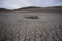 A formerly sunken boat sits on cracked earth hundreds of feet from the shoreline of Lake Mead at th…