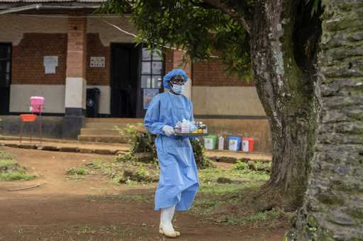 A health worker carries medication to be giving to a man suffering for mpox at the Kamituga General…