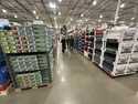 Shoppers make their ways down an aisle lined with clothing and shoes in a Costco warehouse Thursday…