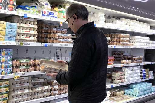 A shopper checks eggs before he purchases at a grocery store in Glenview, Ill