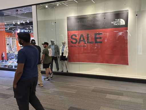 Shoppers pass a sign trumpeting sales at an outlet mall Wednesday, Sept