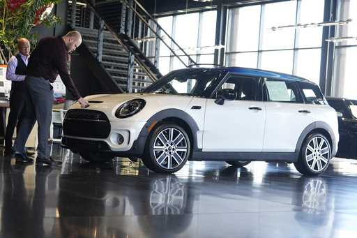 Salesmen examine an unsold 2024 Cooper Clubman S utility vehicle at a Mini dealership May 1, 2024, …