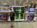 A shopper examines large-screen televisions on display in a Costco warehouse Thursday, Sept