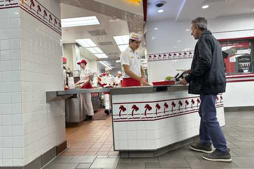 A customer picks up an order at the counter of an In-N-Out Burger restaurant December 8, 2024, in L…