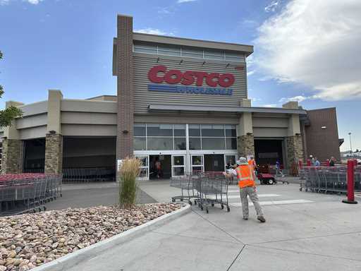 A cart wrangler gathers shopping carts outside a Costco warehouse in Sheridan, Colo