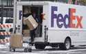 A FedEx delivery person carries a package from a truck on November 17, 2022, in Denver