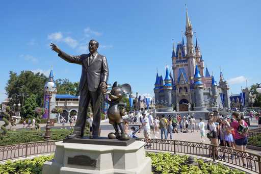 Guests pass a statue of Walt Disney and Mickey Mouse in the Magic Kingdom at Walt Disney World on J…